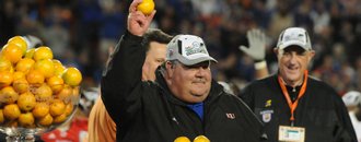 Kansas coach Mark Mangino holds aloft an orange as KU athletic director Lew Perkins, right, looks on.