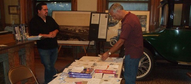 Brian Kuehl, Lawrence, right, picks out his stamp door prize at the beginning of the Sept. 2 meeting of the Lawrence Stamp Club. In background is Devin Zell, club president. The organization has invited the community to its next meeting if they’d like to ask questions about their own collections.
