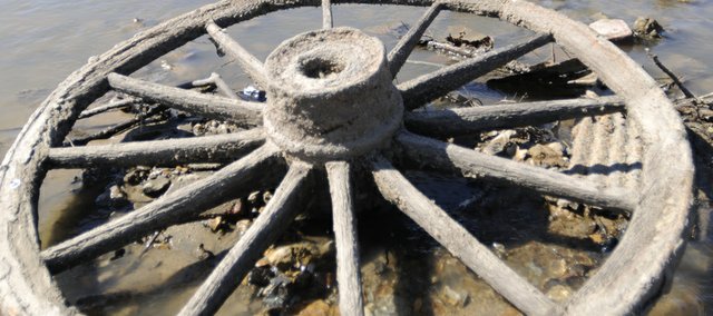 A wagon wheel sits in a low-water area of the Kaw River.