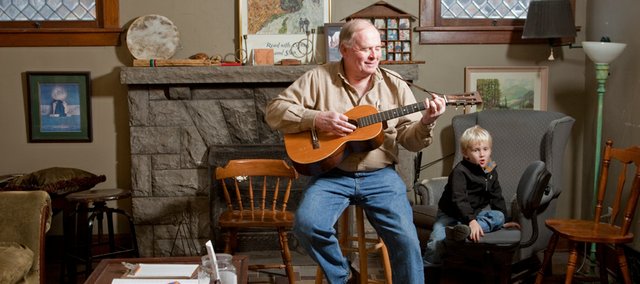 Gary Bennett, a student at Americana Music Academy practices on his early 1900 Washburn guitar with Oliver Davis, 4, nearby. Bennett didn't start playing until he was 67 after his wife began taking fiddle lessons.