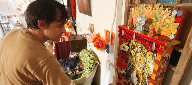 Lawrence artist Paul Punzo places items within an altar he created for a Día de los Muertos event Friday at the Lawrence Percolator, near Ninth and New Hampshire streets. Visitors are invited to create their own altars with pictures, mementos and decorations to pay homage to their loved ones.