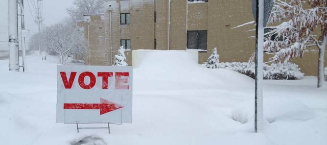 A sign pokes out from the snow to direct Lawrence voters to the Presbyterian Manor polling place Tuesday morning.