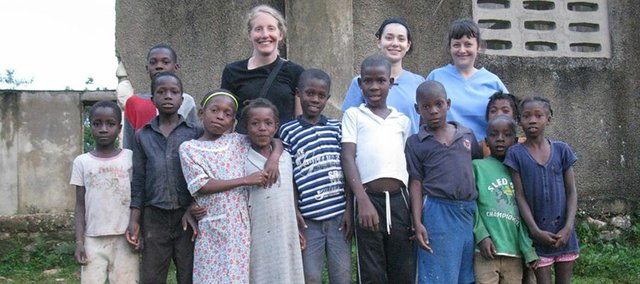 From left, Cindy Mast, a Lawrence physician assistant, Sarah Bradshaw, a Lawrence nursing student, and Shannon Harvey, a former Lawrence resident and nurse, pose for a picture with kids from the Haitian village they provided medical care for last month.