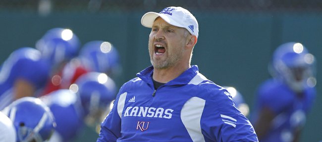 Strength and conditioning coach Scott Holsopple calls out stretches as the Jayhawks get loose for practice on Wednesday, Aug. 15, 2012.