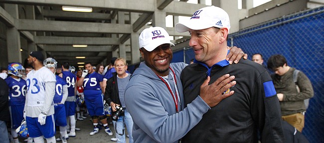 Kansas head football coach David Beaty and Je'Ney Jackson, director of strength and conditioning have a laugh as the team waits under the Memorial Stadium stands as a lightning storm passes during spring practice on Tuesday, March 24, 2015.