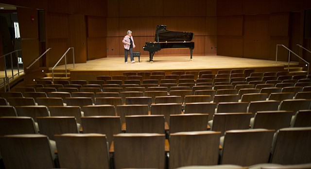 Janet Corwin, special assistant to the dean of the school of Music, tidies up the stage which is graced by a brand new Steinway and Sons grand piano on Thursday, March 19, 2015 at the newly-renovated Swarthout Recital Hall.