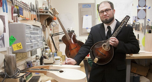 Mike Black, a Lawrence custom builder of mandolins, poses in his shop with an A-style mandolin similar to ones made by the famous Gibson mandolin builder Lloyd Loar. The staged photo is similar to one of famous Gibson mandolin maker Lloyd Loar taken between 1919-1924 in the R&D department at Gibson.
