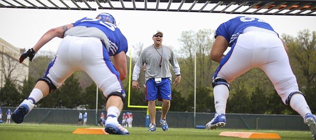 Kansas run game coordinator and offensive line coach Zach Yenser works with the line during practice on Tuesday, April 14, 2015