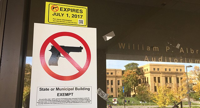 No guns allowed signs are posted on doors leading into Wescoe Hall on the University of Kansas campus on Monday, Oct. 17, 2016. Jayhawk Boulevard and Strong Hall are reflected in the glass.