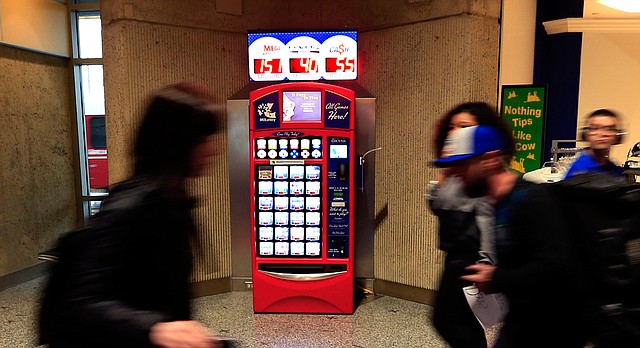 Travelers walk past a Missouri Lottery vending machine at Kansas City International Airport in Kansas City, Mo., Friday, March 24, 2017. Kansas lawmakers are looking to join other states, like Missouri, that allow sales of lottery tickets from vending machines. (AP Photo/Orlin Wagner)