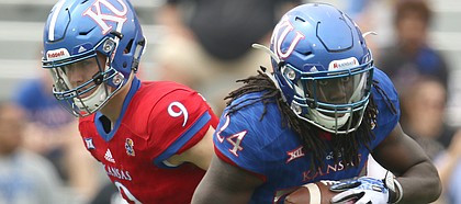 Team KU running back Taylor Martin (24) takes a handoff from Team KU quarterback Carter Stanley (9) during the first quarter of the 2017 Spring Game on Saturday, April 15 at Memorial Stadium.