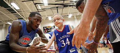 Tyshawn Taylor greets Dagen Korynta, 7, as Dagen runs through a lineup of former KU players during the 2017 Rock Chalk Roundball Classic Thursday evening at Lawrence Free State High School. The annual charity event benefits local families fighting cancer. Dagen was diagnosed with cancer in 2015. As of January 2017, Dagen is in remission.