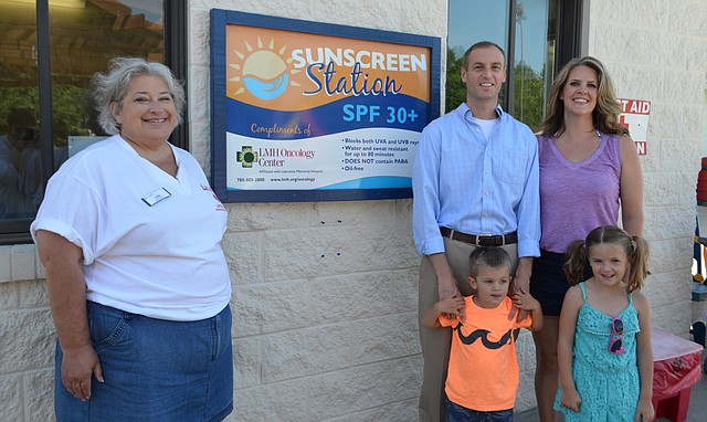 Lawrence Memorial Hospital has installed sunscreen stations at three area swimming pools this summer. Look for signs like this one at the Lawrence outdoor pool, 727 Kentucky St. Pictured are Lori Madaus, aquatics supervisor, as well as Dr. Jared Konie, his wife, Kate, and children, Kelly and Clayton.