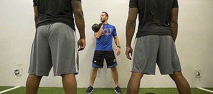 New KU football strength coach Zac Woodfin prepares to lead a warmup session with kettlebells prior to weightlifting at the Anderson Family Football Complex on Thursday, June 29, 2017.