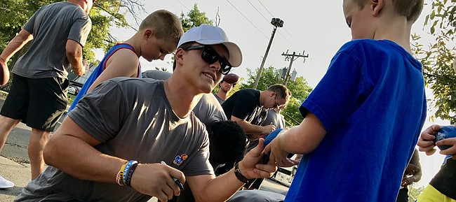 Kansas redshirt sophomore quarterback Carter Stanley greets a young fan and signs a football for him Friday, Aug. 25, 2017, at the KU Kickoff at Corinth Square, in Prairie Village.