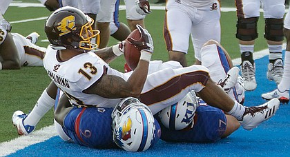 Central Michigan running back Devon Spalding (13) lands on two KU defender after scoring a touchdown in CMU’s win over KU Saturday, Sept. 9 at Memorial Stadium.