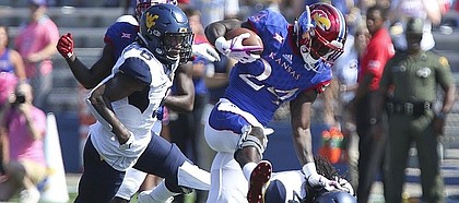 Kansas running back Taylor Martin (24) pushes off of West Virginia cornerback Mike Daniels Jr. (4) on a run during the second quarter on Saturday, Sept. 23, 2017 at Memorial Stadium.