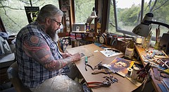 Stained-glass artist John Niswonger works to cut glass pieces for a "Texas Chainsaw Massacre" sun catcher ordered from a buyer in Canada, Tuesday, Sept. 26, 2017 in the studio of his Lake Dabinawa home.