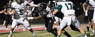 Free State senior quarterback Gage Foster puts a stiff arm on Lawrence High linebacker Ja'Relle Dye (14) during the second quarter of the City Showdown on Friday, Oct. 20, 2017 at LHS.