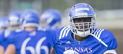 Kansas offensive lineman Hakeem Adeniji runs through warmups on Friday, Aug. 18, 2017 at the grass fields adjacent to Hoglund Ballpark.