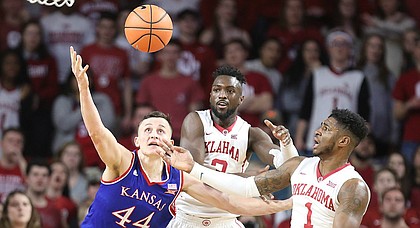 Kansas forward Mitch Lightfoot (44) fights for a ball with Oklahoma forward Khadeem Lattin (3) and Oklahoma guard Rashard Odomes (1) during the first half at Lloyd Noble Center on Tuesday, Jan. 23, 2018 in Norman, Oklahoma.