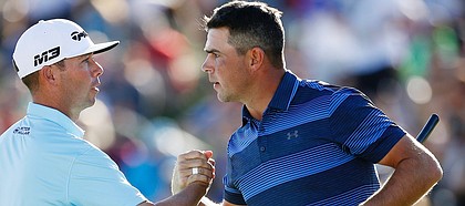 After winning a one-hole playoff, Gary Woodland, right, shakes hands with Chez Reavie, left, on the 18th green during the final round of the Waste Management Phoenix Open golf tournament Sunday, Feb. 4, 2018, in Scottsdale, Ariz. (AP Photo/Ross D. Franklin)