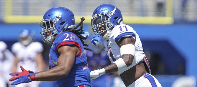 Kansas safety Mike Lee (11) smiles as he chases Kansas running back Kendall Morris (28) during an open practice on Saturday, April 28, 2018 at Memorial Stadium.