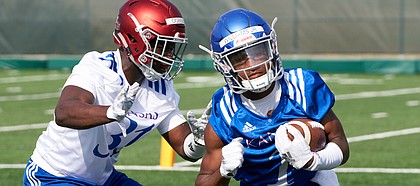 Kansas freshman running back Pooka Williams scoots past senior linebacker Osaze Ogbebor during practice drills on Aug. 4, 2018