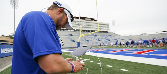 FILE — Jeff Love gets a live view from a drone on an iPad, which connects directly into the aircraft's flight controller during practice on Monday, Aug. 15, 2016 at Memorial Stadium. Love now serves as a full-time assistant on the Kansas football staff, which had a spot open midseason once David Beaty fired Doug Meacham.