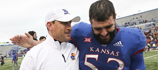 Kansas offensive lineman Alex Fontana (53) puts his arm around Kansas head coach David Beaty as Beaty leaves the field for the last time as head coach after losing 24-17 against Texas at Memorial Stadium.