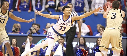 Kansas guard Devon Dotson (11) reaches for a pass to Wofford guard Fletcher Magee (3) as he defends the perimeter during the second half on Tuesday, Dec. 4, 2018 at Allen Fieldhouse.