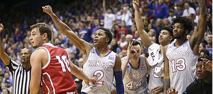 Kansas guard Charlie Moore (2) hangs his hand in the air after putting up a three from the corner over South Dakota guard Cody Kelley (10) as the bench celebrates during the second half, Tuesday, Dec. 18, 2018 at Allen Fieldhouse.