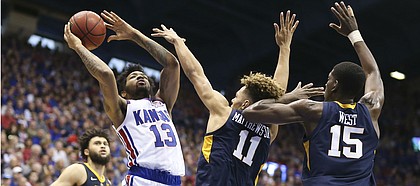 Kansas guard K.J. Lawson (13) hangs for a shot against West Virginia forward Emmitt Matthews Jr. (11) and West Virginia forward Lamont West (15) during the second half, Saturday, Feb. 16, 2019 at Allen Fieldhouse.