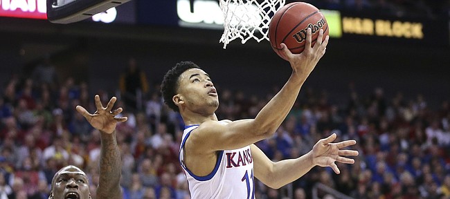 Kansas guard Devon Dotson (11) squeezes under the bucket past Iowa State forward Cameron Lard (2) and Iowa State guard Lindell Wigginton (5) for a shot during the first half, Saturday, March 16, 2019 at Sprint Center in Kansas City, Mo.