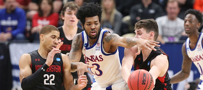 Kansas guard K.J. Lawson (13) looks to disrupt a pass between Northeastern guard Donnell Gresham Jr. (22) and Northeastern forward Tomas Murphy (33) during the first half, Thursday, March 21, 2019 at Vivint Smart Homes Arena in Salt Lake City, Utah.