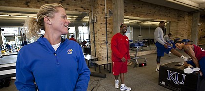 Andrea Hudy turns over her shoulder to laugh with players Thomas Robinson, Niko Roberts and assistant strength and conditioning coach Glenn Cain during a workout session. Nick Krug/Journal-World Photo