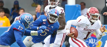 Oklahoma quarterback Jalen Hurts (1) gets away from Kansas linebacker Gavin Potter (19) and Kansas linebacker Azur Kamara (5) during the third quarter on Saturday, Oct. 5, 2019 at Memorial Stadium.