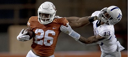 Texas running back Keaontay Ingram (26) stiff-arms Kansas cornerback Hasan Defense (13) during an NCAA college football game Saturday, Oct. 19, 2019, in Austin, Texas. (Nick Wagner/Austin American-Statesman via AP)