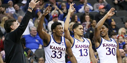 Kansas redshirt Mitch Lightfoot, left, forward David McCormack (33) and guards Tristan Enaruna (13) and Ochai Agbaji (30) celebrate a three from Kansas guard Chris Teahan (12) during the second half, Saturday, Dec. 14, 2019 at Sprint Center in Kansas City, Mo.