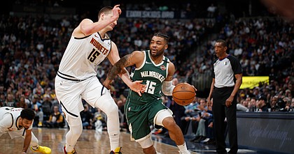 Milwaukee Bucks guard Frank Mason III (15) drives past Denver Nuggets center Nikola Jokic (15) in the second half of an NBA basketball game Monday, March 9, 2020, in Denver.