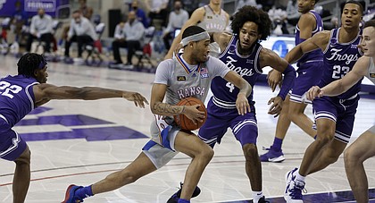Kansas guard Dajuan Harris, center, drives to the basket as TCU guard RJ Nembhard (22), guard PJ Fuller (4) and forward Jaedon LeDee (23) defend in the first half of an NCAA college basketball game in Fort Worth, Texas, Tuesday, Jan. 5, 2021. (AP Photo/Ron Jenkins)