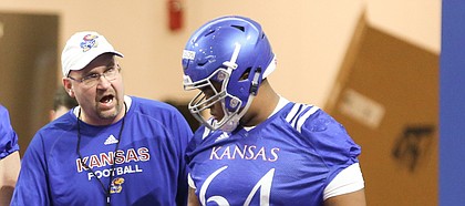 Kansas offensive line coach Luke Meadows gives instruction to lineman Jalan Robinson (54) during football practice on Wednesday, March 6, 2019 within the new indoor practice facility.