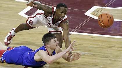 Kansas guard Christian Braun (2) and Oklahoma guard Umoja Gibson (2) fight for the ball during the first half of an NCAA college basketball game in Norman, Okla., Saturday, Jan. 23, 2021. (AP Photo/Garett Fisbeck)