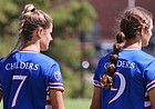 Sisters and Kansas soccer teammates Raena (No. 7) and Rylan Childers (No. 9) hold hands on the sideline before a game.