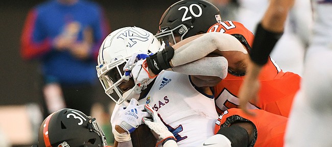 Kansas running back Devin Neal (4) is brought down shy of a first downm forcing a turnover on downs, by Oklahoma State safety Kolby Harvell-Peel (31), safety Sean Michael Flanagan (18) and linebacker Malcolm Rodriguez (20) during the first quarter of an NCAA college football game Saturday, Oct. 30, 2021, in Stillwater, Okla. (AP Photo/Brody Schmidt)