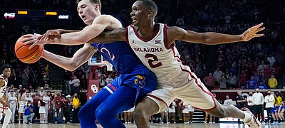 Kansas guard Christian Braun, left, is fouled by Oklahoma guard Umoja Gibson (2) in the second half of an NCAA college basketball game Tuesday, Jan. 18, 2022, in Norman, Okla. (AP Photo/Sue Ogrocki)