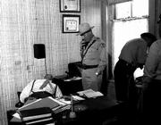 A sheriff's deputy uses Leroy Harris' office telephone as two
Lawrence Police officers collect evidence for his murder
investigation. The crime scene photos were taken by Rich Clarkson,
now a nationally known photographer, who was a Kansas University
student working part-time for the Journal-World in 1954.