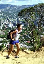 A Venezuelan woman hikes up a trail in El Avila National Park with
the city of Caracas in the background. Perched between Caracas and
the towns that line Venezuela's Caribbean coast, the Avila mountain
ridge is nature's lofty fortress amid one of South America's most
urbanized areas.
