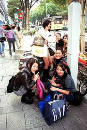 A group of young women take time out from their shopping in Tokyo's
Shibuya to rest and, in some cases, smoke a cigarette. Smoking is
still very popular in Japan.