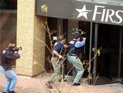 Armed Lawrence police officers approach Firstar Bank responding to
a hostage/robbery standoff. Prior to making their move, police
cordoned off much of a two-block downtown area during the lunch
hour Wednesday.